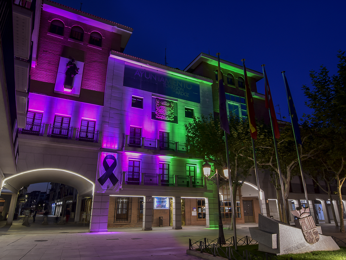 La fachada del Ayuntamiento de Torrejón de Ardoz iluminada de verde y morado