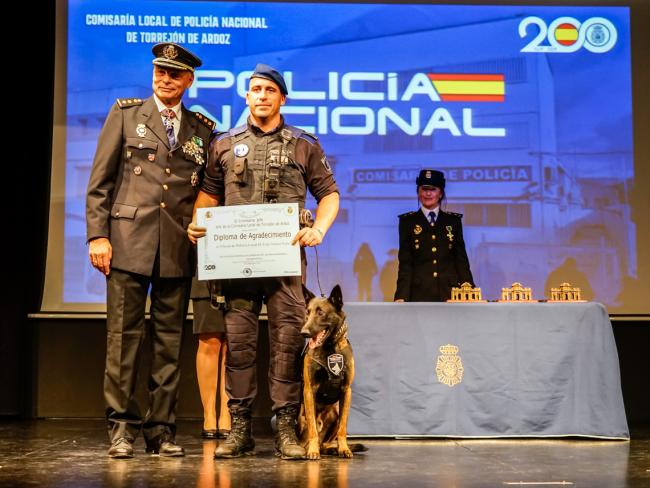 El comisario del Cuerpo Nacional de Policía en Torrejón de Ardoz, Juan Ignacio Parreño y el oficial de la Policía Local de Torrejón de Ardoz, Iván Solera Vela, posando con el diploma entregado junto a Hulk, uno de los perros de la Unidad Canina torrejonera 